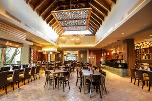 Innenraum des Restaurants im Vista Sol Punta Cana Beach Resort & Spa mit geometrischen Deckenleuchten und Holzboden.