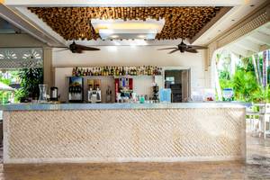 Innenansicht der Bar im Vista Sol Punta Cana Beach Resort & Spa mit gefliester Theke und Tropenpflanzen im Hintergrund.