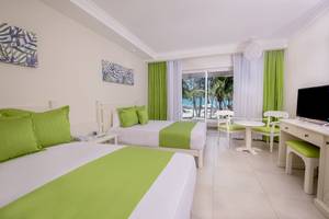 Zimmer im Vista Sol Punta Cana Beach Resort & Spa mit zwei Betten und grünen Kissen.