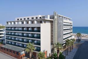 Aquila Porto Rethymno Hotelgebaude am Meer mit Palmen und Sonnenschein