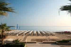 Strandansicht des Aquila Porto Rethymno Hotels mit vielen Sonnenschirmen und Liegestühlen