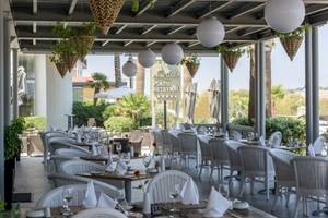 Außenbereich des Aquila Porto Rethymno Hotels mit weißen Stühlen und Tischen.