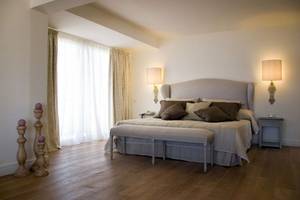 Schlafzimmer im Aquila Porto Rethymno Hotel mit Holzboden und weißen Wänden.