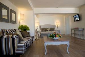 Hotelzimmer im Aquila Porto Rethymno mit Bett, Couch, Tisch und Fernseher.