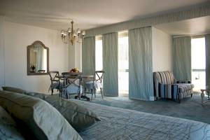 Schlafzimmer im Aquila Porto Rethymno Hotel mit Bett, Esstisch, Stühlen und Spiegel.