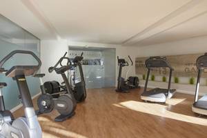 Fitnessbereich im Pure Salt Garonda Hotel mit mehreren Cardiogeräten und Sonnenlicht.
