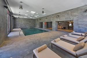 Innenansicht des Schwimmbereichs im Pure Salt Garonda Hotel mit grünem Wasser und Lounge-Liegen.