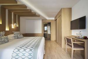 Innenansicht eines Hotelzimmers im Pure Salt Garonda mit Bett, Schreibtisch und Fernseher.