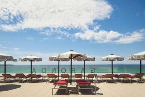 Außenbereich des Pure Salt Garonda Hotels mit Liegen, Sonnenschirmen und Meerblick.
