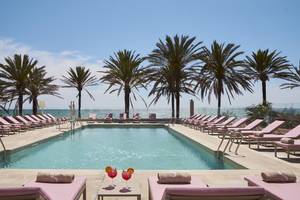 Pool-Loungebereich mit Palmen und Getränken im Pure Salt Garonda Hotel