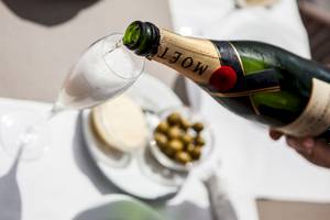 Ein Champagner wird in ein Glas gegossen, serviert mit Oliven und Käse.