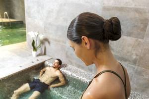 Eine Frau schaut in einen Innenpool, in dem ein Mann liegt, im Pure Salt Garonda Hotel.