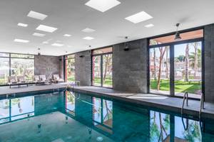 Poolbereich im Pure Salt Garonda Hotel mit Lounge-Sesseln und Glastüren