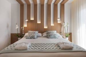 Schlafzimmer im Pure Salt Garonda Hotel mit Bett, Kissen, Nachttischen und Pflanzen.