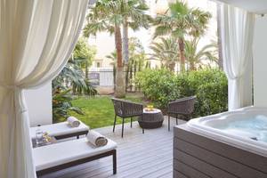 Terrasse des Pure Salt Garonda Hotels mit Whirlpool, Liegen und Tischen im Freien.