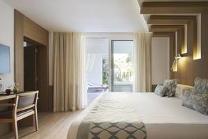 Schlafzimmer im Pure Salt Garonda Hotel mit Bett, Schreibtisch und Zugang zur Terrasse.