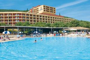 Außenbereich des Atlantica Nissaki Beach Hotels mit Swimmingpool, Sonnenliegen und Gästen.