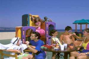 Familie genießt Kinderanimation im Atlantica Nissaki Beach Hotel mit Blick auf das Meer.
