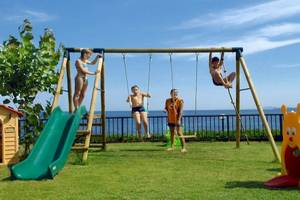 Kinder spielen auf einem Spielplatz im Freien im Atlantica Nissaki Beach Hotel.