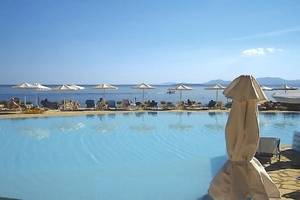 Außenpoolbereich des Atlantica Nissaki Beach Hotels mit Sonnenschirmen und Liegestühlen.