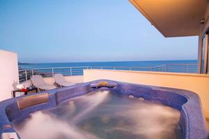 Whirlpool auf dem Balkon mit Blick auf das Meer und zwei Liegestühlen