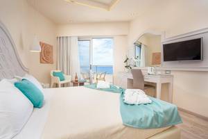 Pegasos Deluxe Beach Hotel Zimmer mit Meerblick, Bett, Sessel, Schreibtisch und Fernseher.