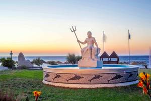 Statue am Strand im Pegasos Deluxe Beach Hotel bei Sonnenuntergang
