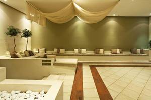 Loungebereich im Kipriotis Hippocrates Hotel mit Sofas, Pflanzen und Fliesenboden.