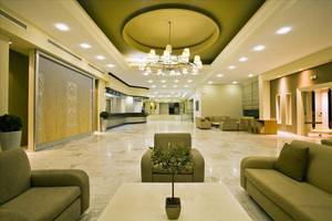 Lobby des Kipriotis Hippocrates Hotels mit Marmorboden, Couchen, und einer Pflanze auf dem Tisch.