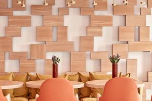 Lobby des Myconian Naia Hotels mit Sofas und Tischen vor einer Holzwand