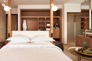 Schlafzimmer im Myconian Naia Hotel mit Steinwand, Holzschrank und frischem Obst auf dem Tisch.