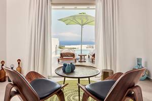 Innenraum des Myconian Naia Hotels mit Blick auf das Meer und ein grüner Sonnenschirm.