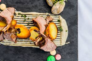 Lammkoteletts und Kartoffeln auf einer schwarzen Platte im Myconian Naia Hotel