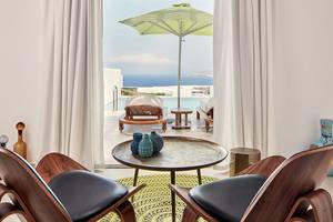Innenansicht des Wohnzimmers im Myconian Naia Hotel mit modernem Möbeldesign und Blick auf das Meer.