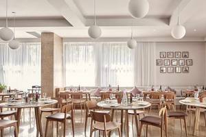 Innenansicht des Restaurants im Atlantica Marmari Palace mit runden Lampen und Tischstühlen.