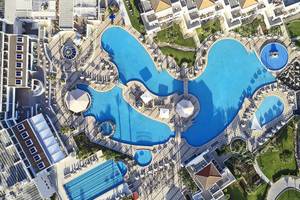 Luftaufnahme des Swimmingpools im Atlantica Marmari Palace Hotel mit mehreren Becken und Sonnenliegen.