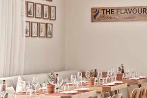 Innenbereich des The Flavour Spezialitäten Restaurant mit eingerichteten Tischen und Stühlen.
