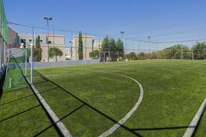 Sportplatz des Atlantica Marmari Palace Hotels mit grünem Kunstrasen und Umzäunung.