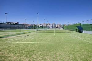 Tennisplatz im Atlantica Marmari Palace mit leeren Spielfeldern und umliegenden Gebäuden.