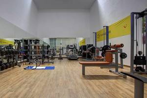 Fitness-Center im Atlantica Marmari Palace Hotel mit verschiedenen Trainingsgeräten und einer hölzernen Fitnessfläche.