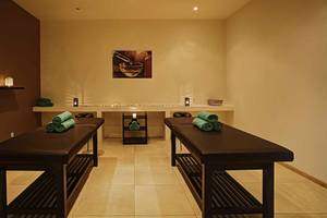 Massage-Salon im Atlantica Marmari Palace mit zwei Massagetischen und grünen Handtüchern.