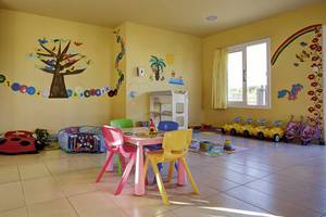 Kinderzimmer im Atlantica Marmari Palace mit bunten Wandmalereien, bunten Stühlen und Spielzeug.