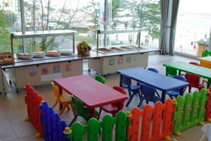 Kinderspielzimmer im Sentido Golden Star Hotel mit bunten Tischen, Stühlen und einem Blick auf das Meer.