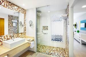 Badezimmer im Playa Vista Azul Hotel in Varadero mit gefliester Wand, Dusche und Waschbecken.