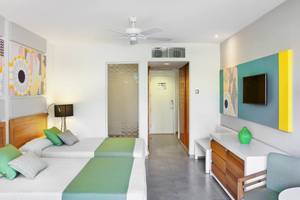 Zwei Betten mit grünen Kissen in einem modernen Zimmer im Playa Vista Azul Varadero Hotel.