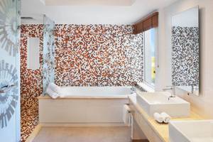 Ein Badezimmer mit einer Badewanne und einer braun-weiß gemusterten Fliesenwand.