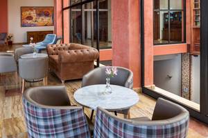 Hotel-Lounge-Bereich im Occidental Jandia Royal Level mit braunem Sofa und mehreren Sesseln um einen Tisch.