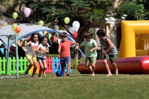 Kinder spielen auf einer Rasenfläche im Freizeitpark des Kempinski Hotel Residences Palm Jumeirah.