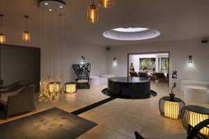 Innenbereich des Cocoon Maldives Hotels mit Loungebereich, Couch und Lichtinstallationen.