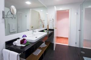 Badezimmer im Fuerteventura Princess Hotel mit Spiegel, Waschbecken und offenen Türen zur Dusche.
